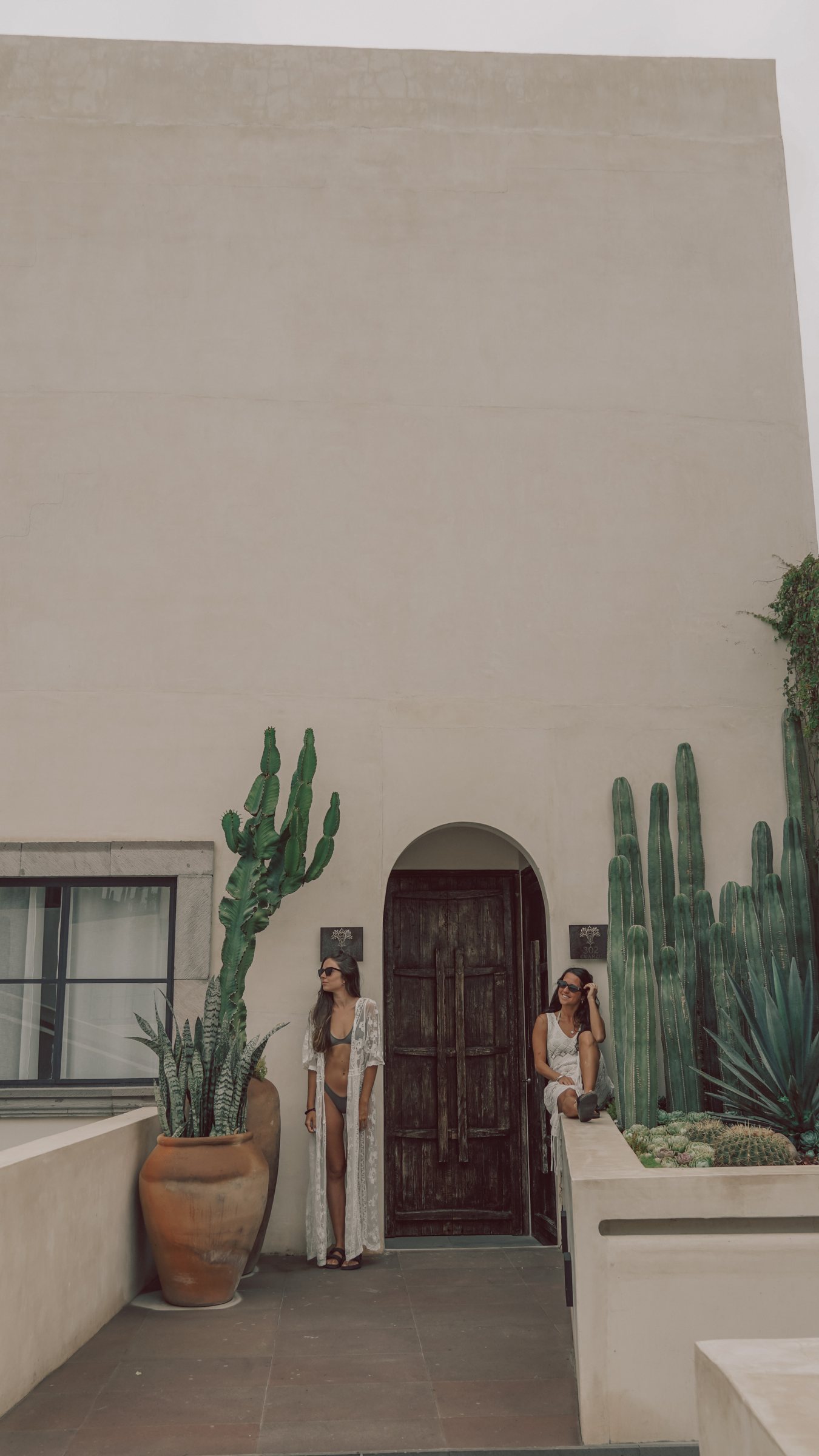 Pau y Juli frente a una puerta de madera rodeada de cactus